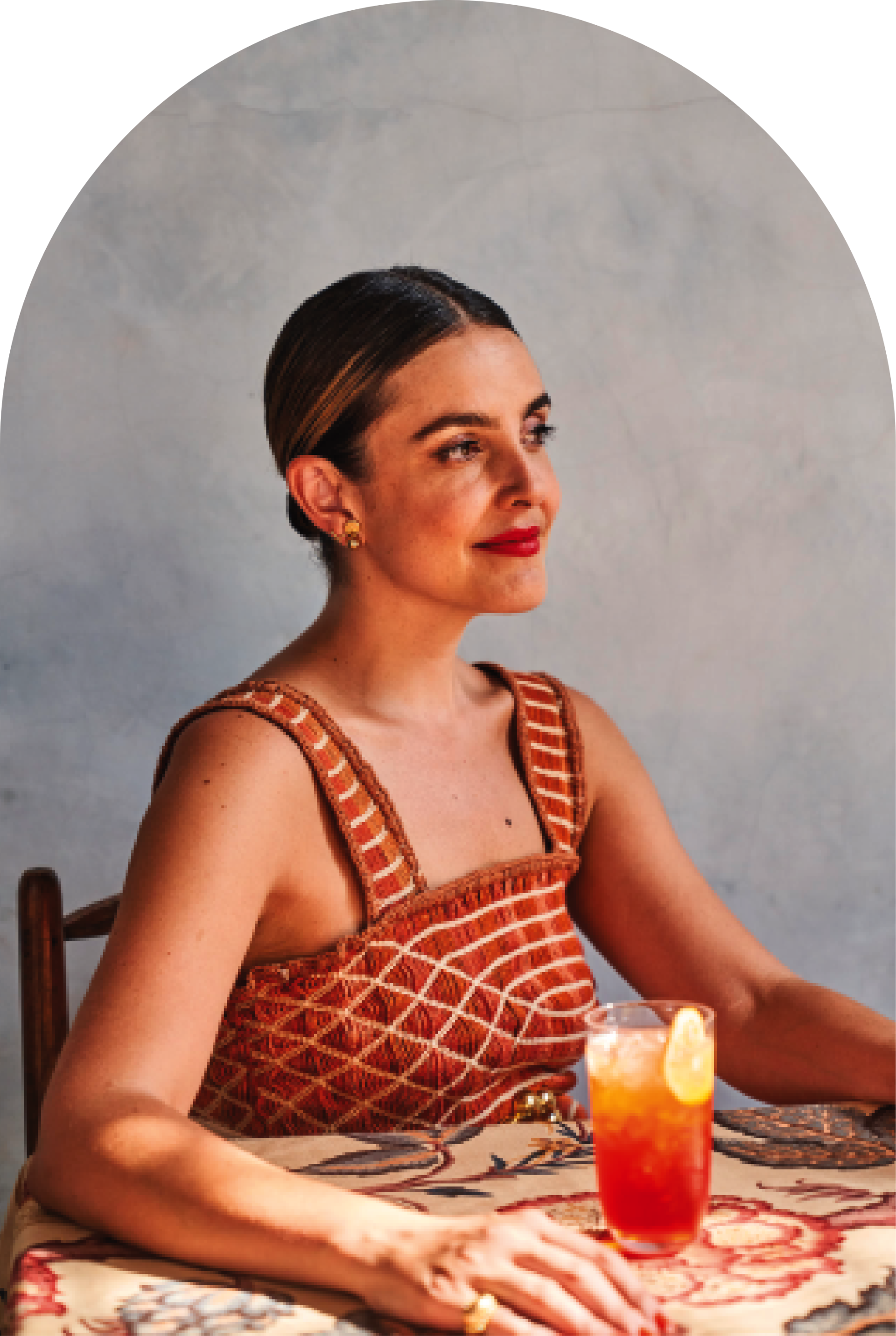 A woman is sitting at a table with a drink in her hand.