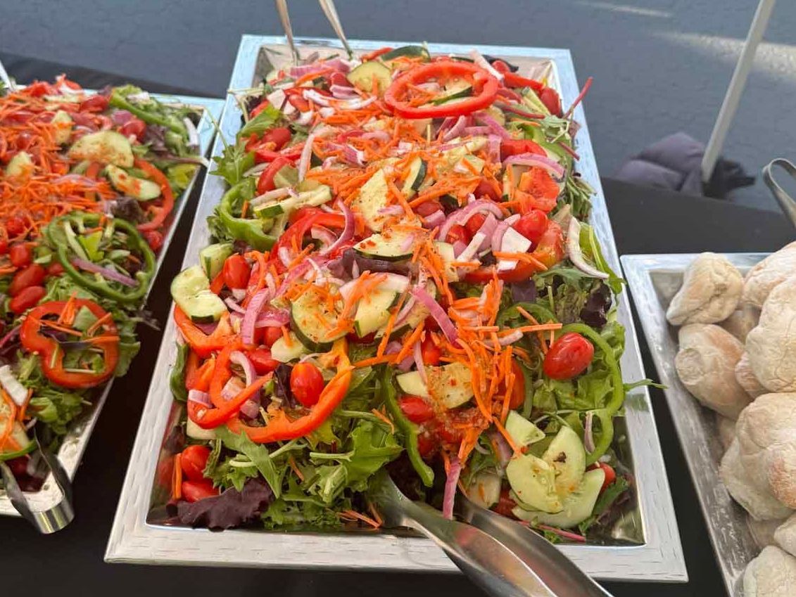 A buffet table with a salad and mushrooms on it.