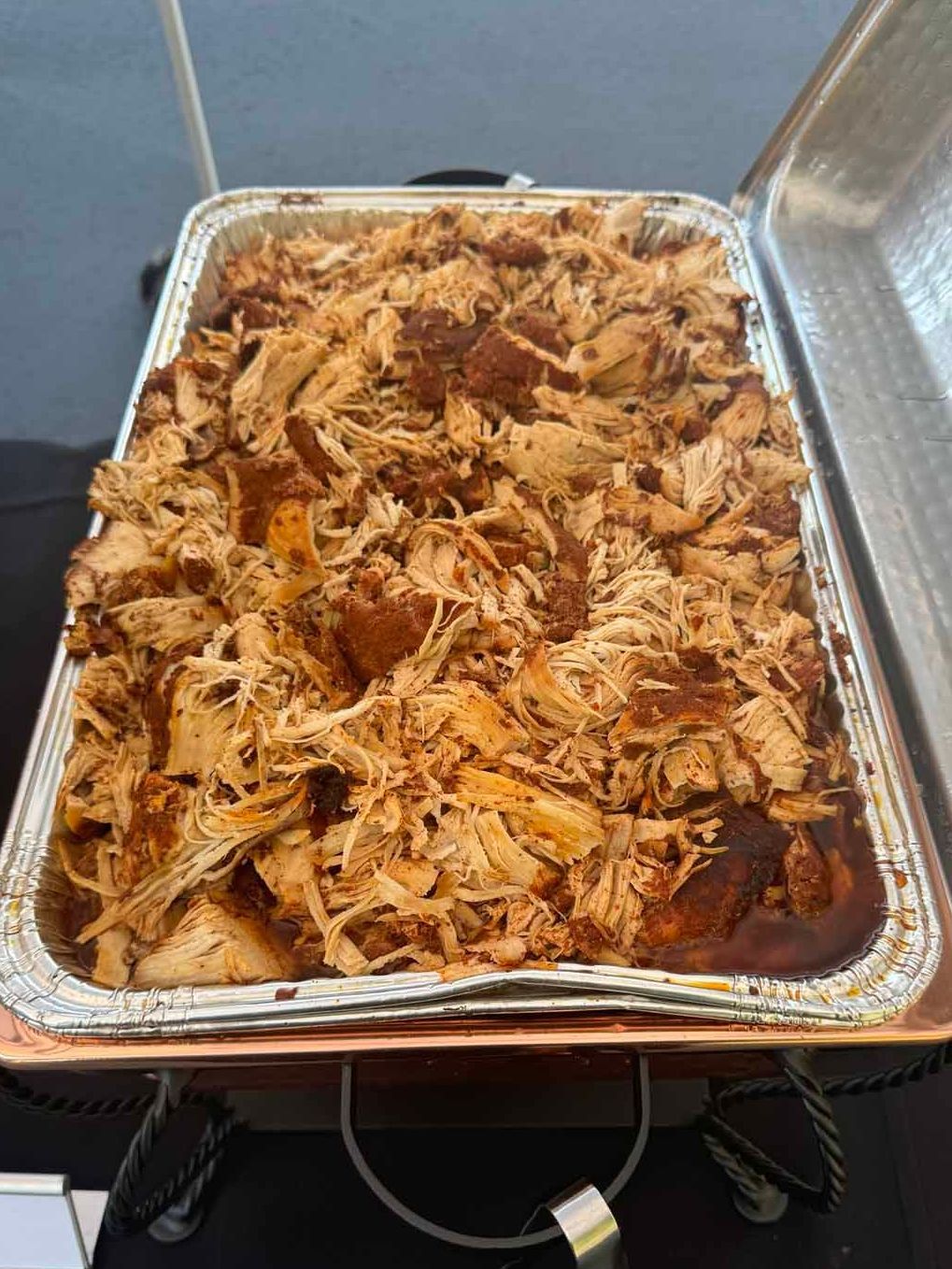 A tray of pulled pork is sitting on top of a buffet table.