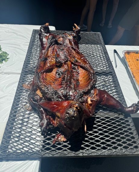 A roasted pig is laying on its back on a grill.