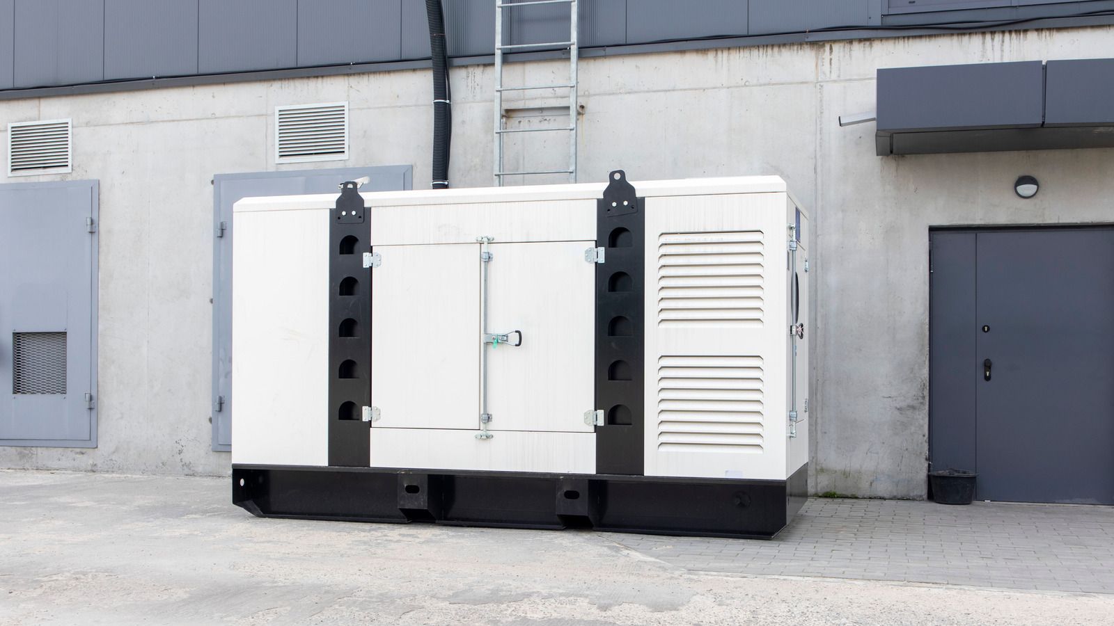 A large white generator is parked in front of a building.