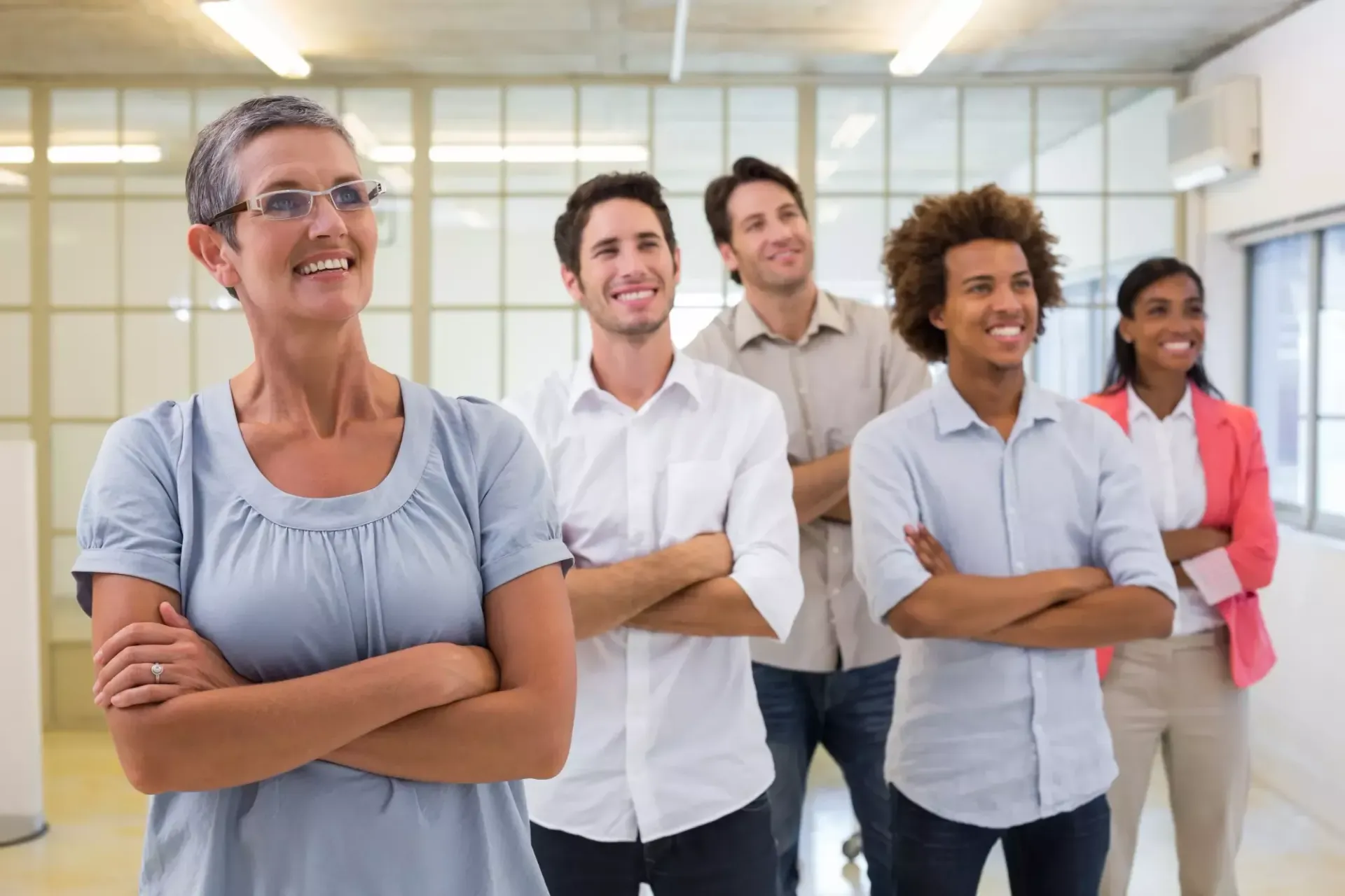 Um grupo de pessoas está em fila com os braços cruzados e sorrindo.