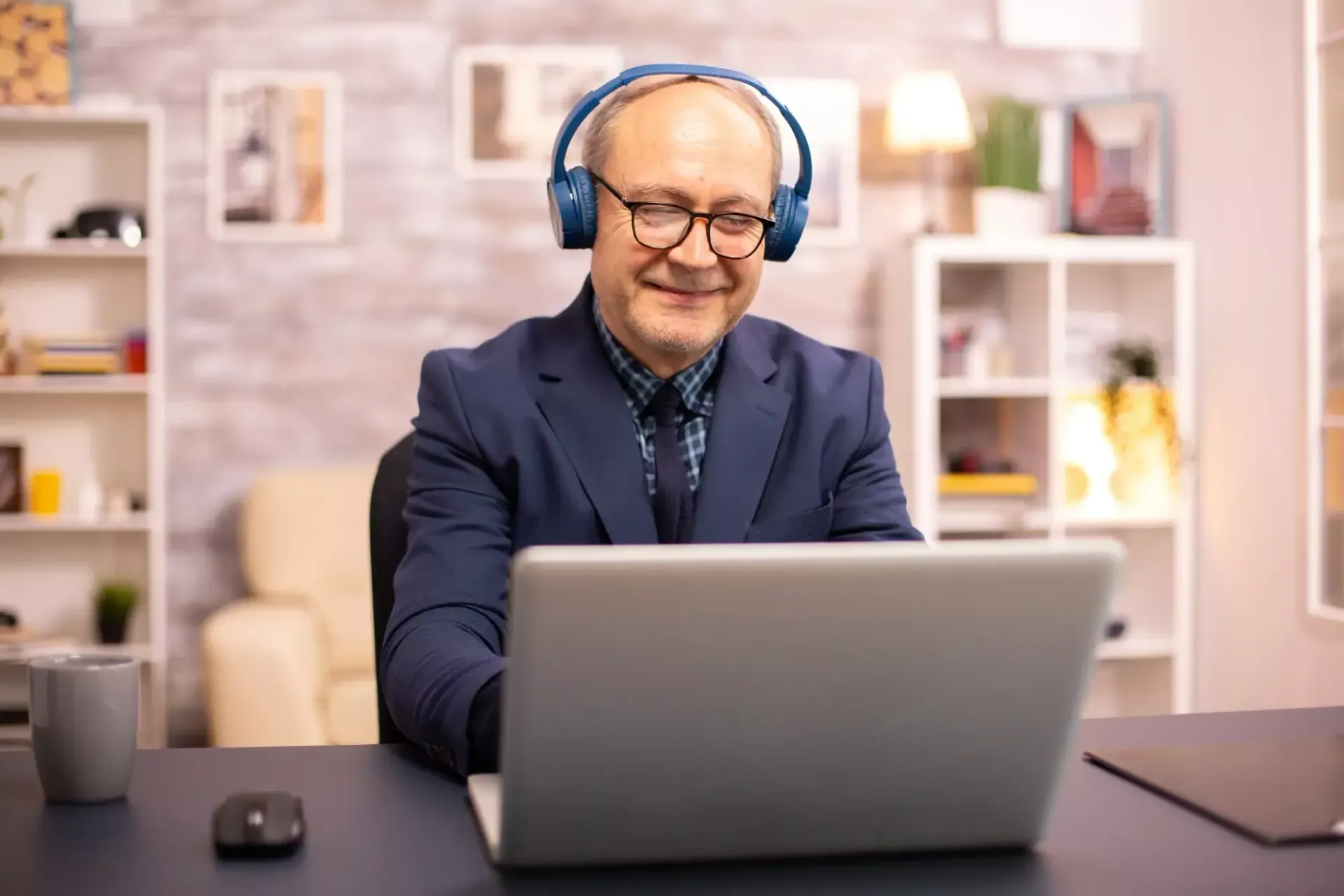 Um homem usando fones de ouvido está sentado em frente a um laptop.
