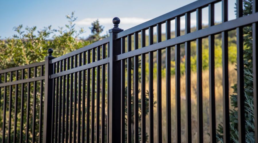 Newly installed black aluminum perimeter fence with ball post caps.