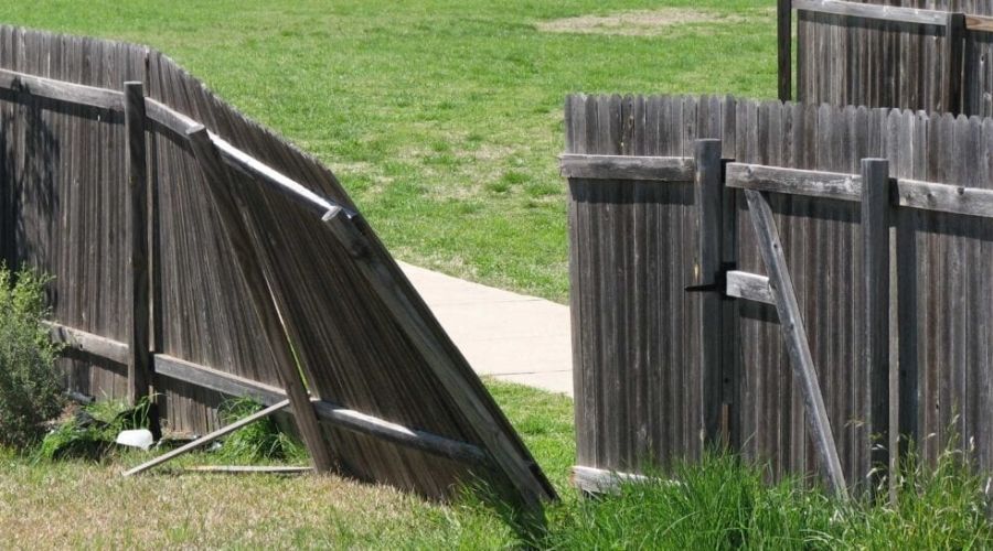 Broken and collapsed wooden privacy fence section caused by damaged support posts.