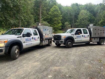 Man stands next to a Legacy Fence work truck. Truck is white with toolboxes, in grassy area with trees.