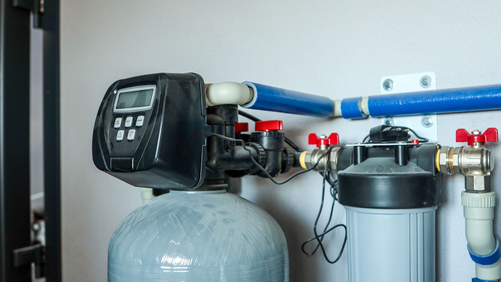 Water softener services system with filtration tank and control valve installed in home utility room. Water softener services system with filtration tank and control valve installed in home utility room.