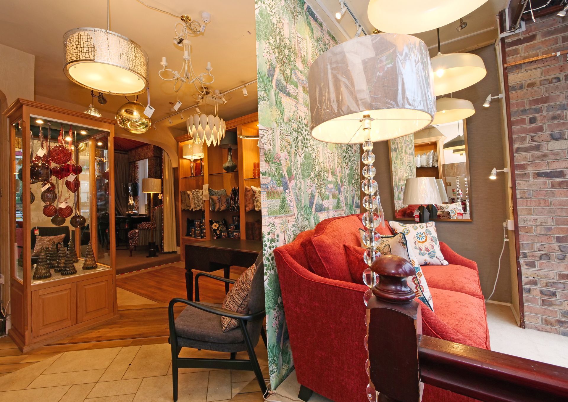 A showroom featuring a red sofa and a floor lamp with a crystal stand next to a wall covered in patterned wallpaper.