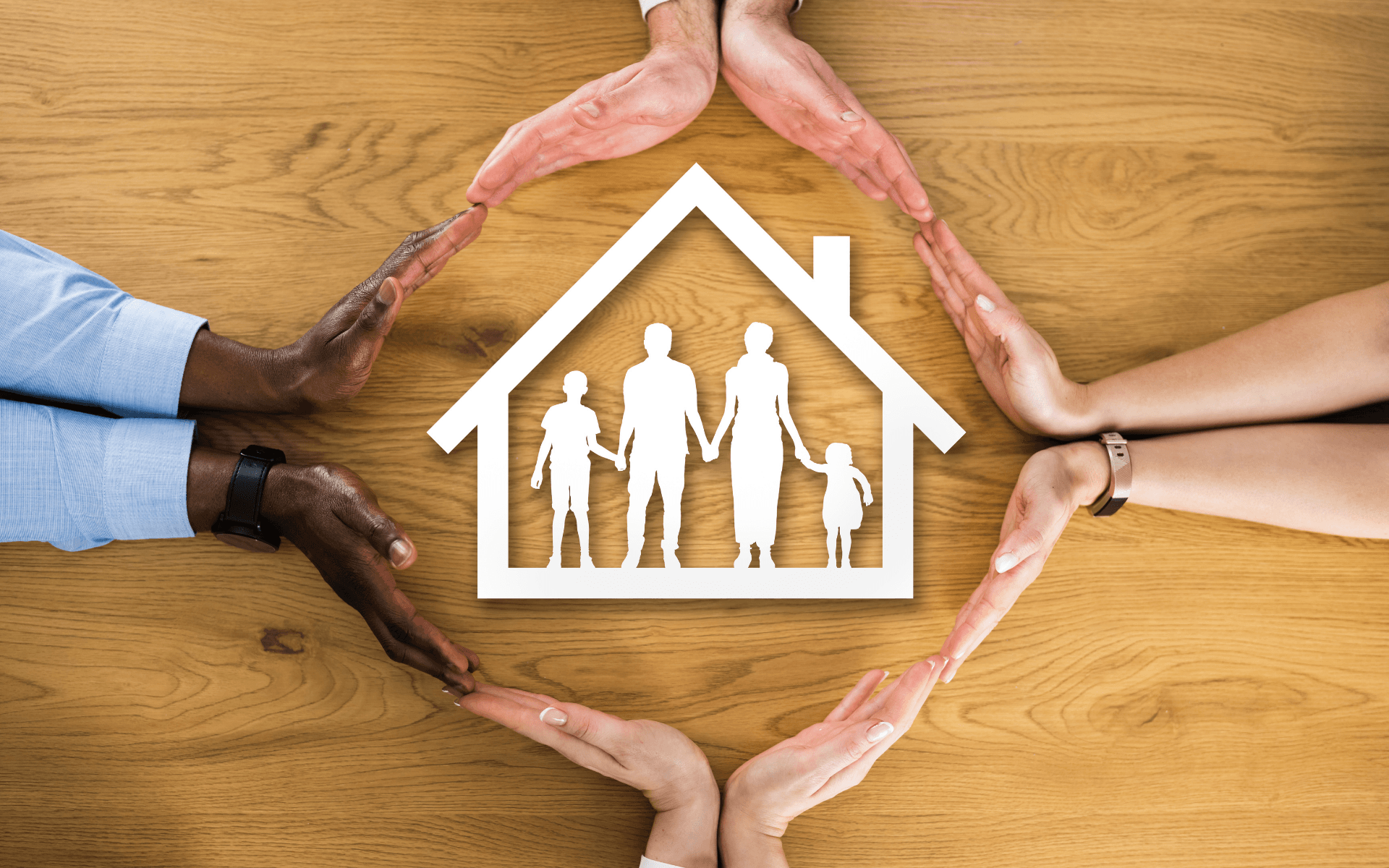 A group of people are making a circle with their hands around a house.