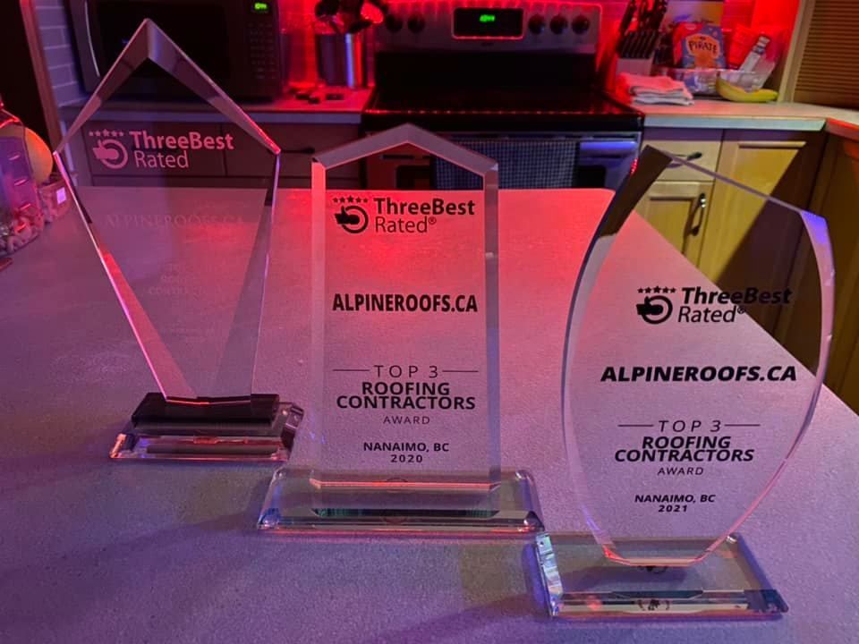 Three trophies are sitting on a table in front of a stove.
