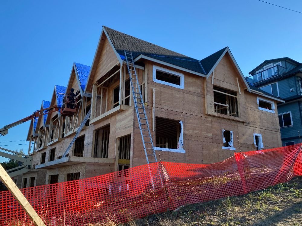 A large house is being built on a hill with a fence around it.