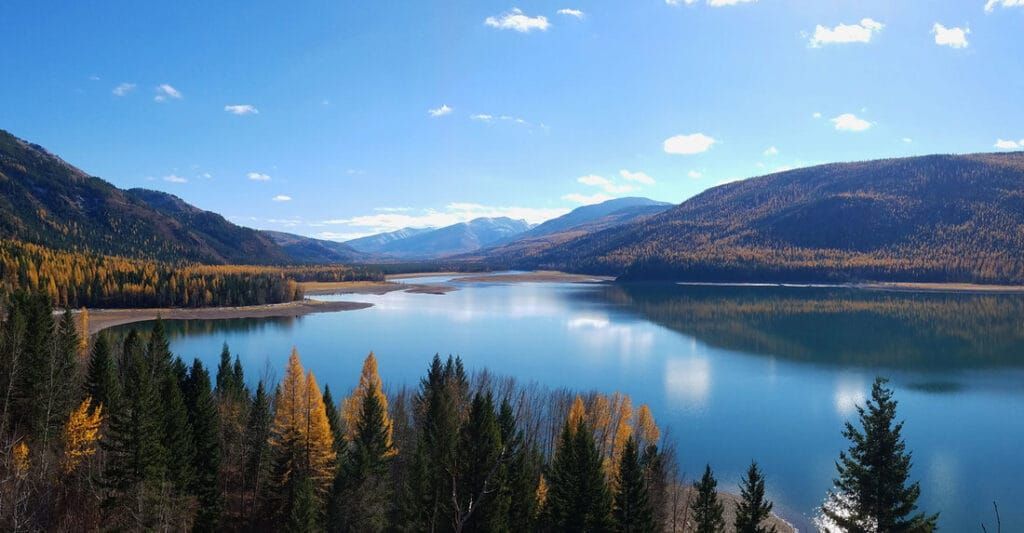 A large lake surrounded by mountains and trees on a sunny day.