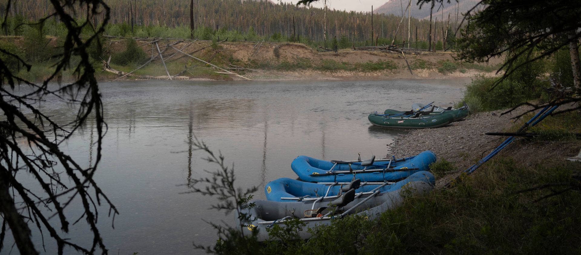 Two blue rafts are sitting on the shore of a river.