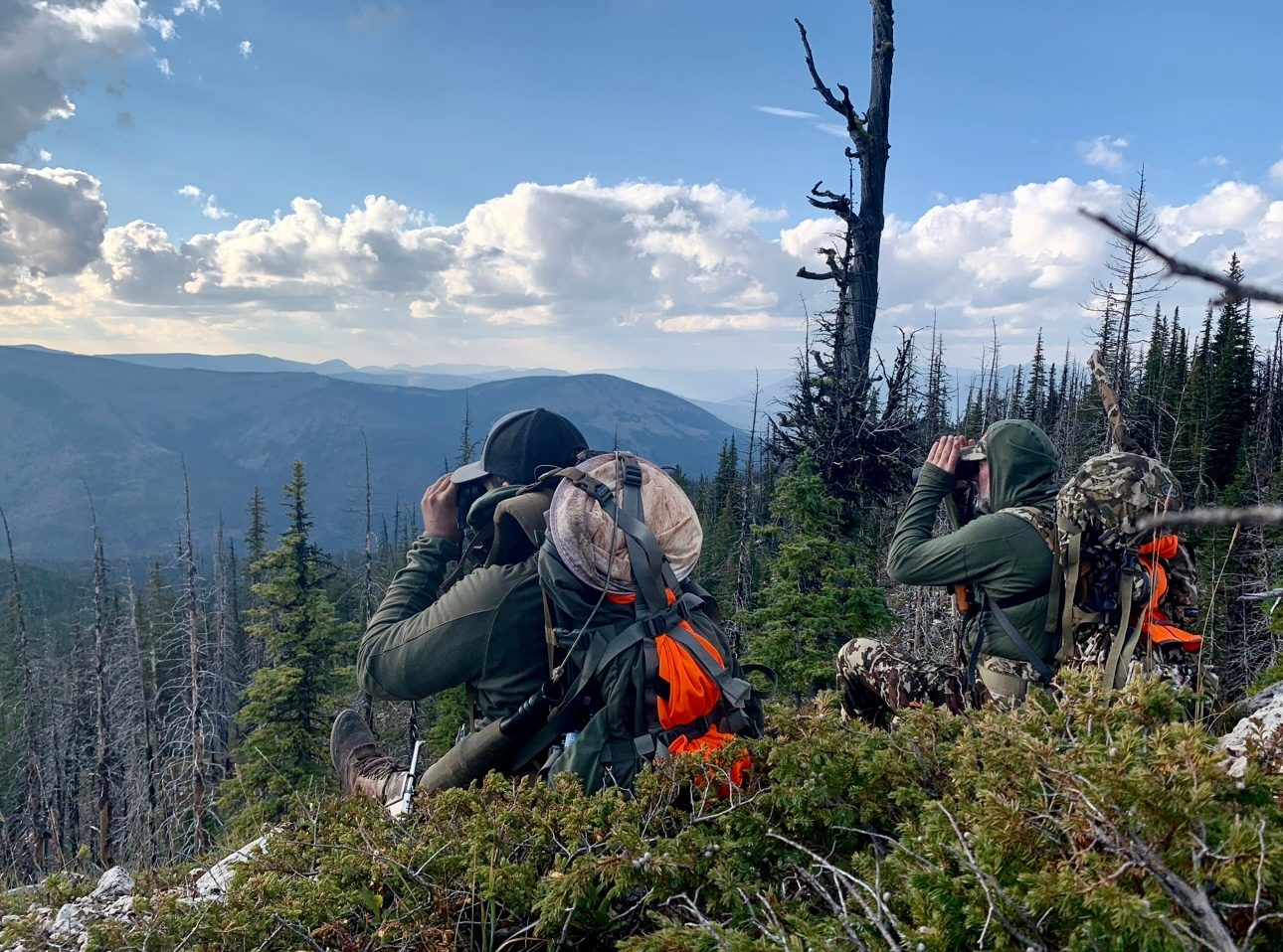 A group of people are sitting on top of a mountain looking through binoculars.