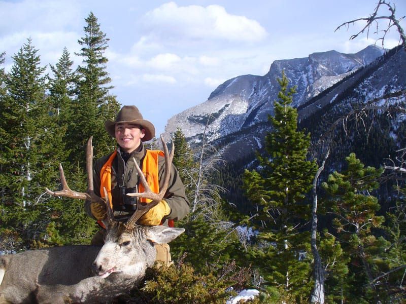 man holding antlers of mountain deer
