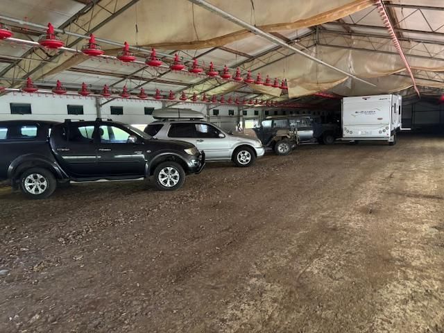A Row Of Cars Are Parked In A Dirt Lot Under A Tent — Byron Storage Services In Myocum, NSW