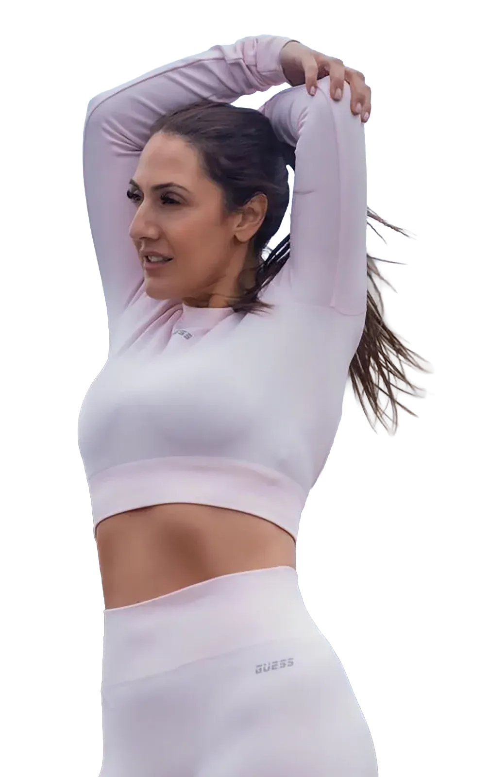 Woman in a light lavender athletic outfit stretching with arms raised overhead outdoors.