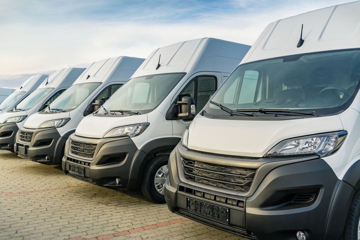 A white semi-truck parked with its hood open, exposing the engine, against a cloudy, bright sky.