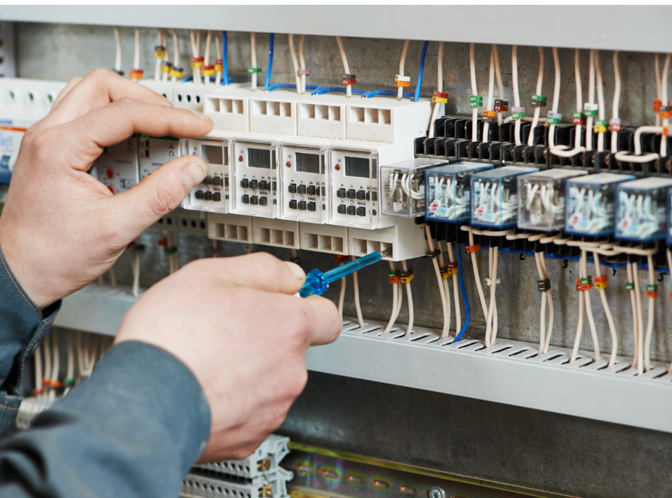 A man is working on an electrical panel with a screwdriver.