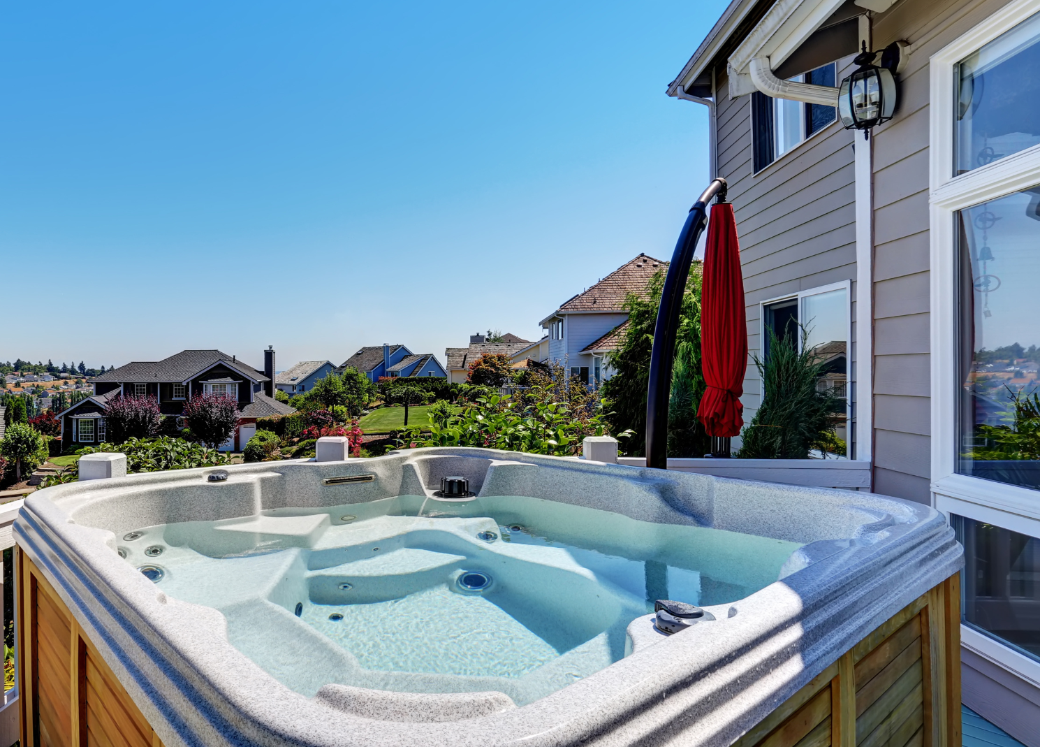 A hot tub is sitting on the deck of a house.