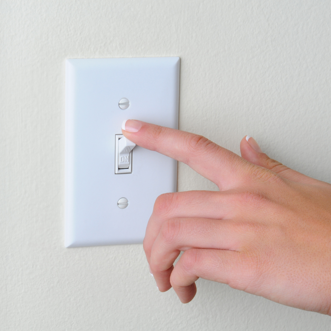A person is pressing a light switch with their finger