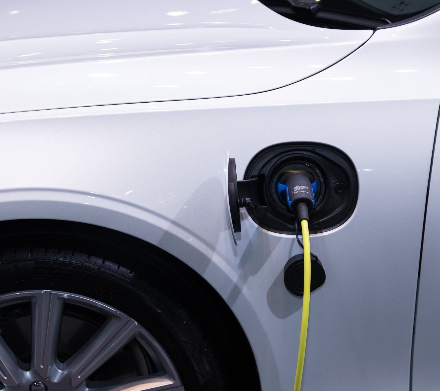 A white car is being charged with a yellow cord