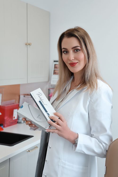 Hula Castellon, FNP, MSN, and owner of Uplifted Aesthetics holding product boxes.