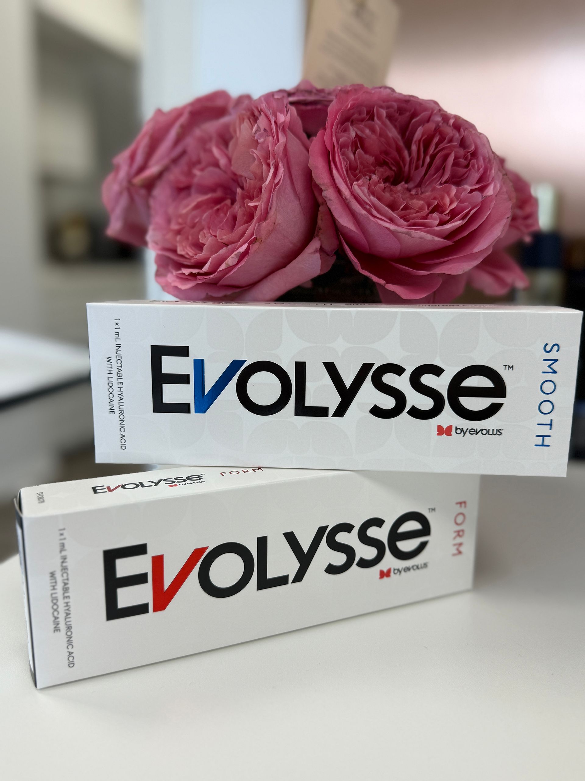 Two boxes of Evolysse skin cream, stacked, with pink roses in the background.