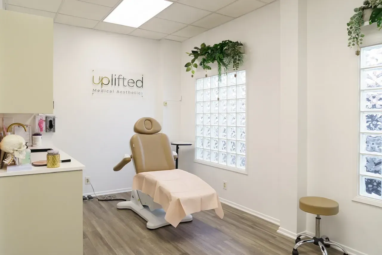 A light and airy aesthetician's office with a treatment chair, window, and plants.