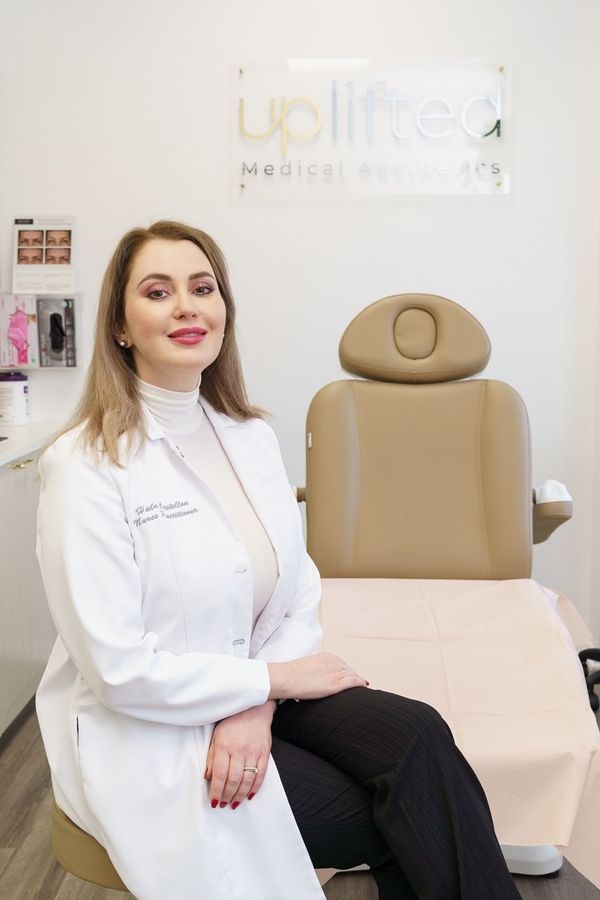 Hula Castellon, FNP, MSN, and owner of Uplifted Aesthetics  sitting by medical chair, before a treatment.