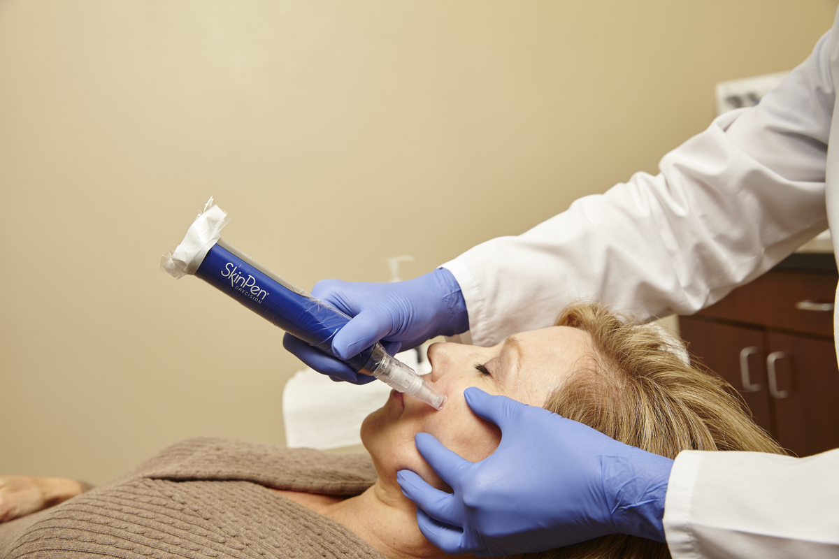 Person receiving a facial treatment. A medical professional holds a device near the person's face.