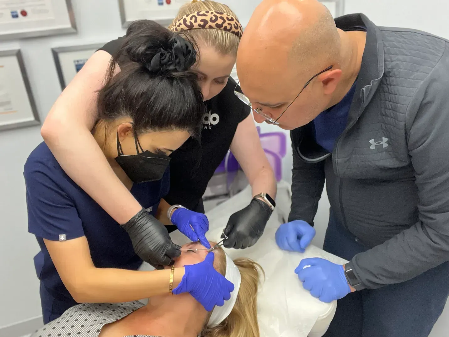 Medical professionals performing a procedure on a patient's face, indoor setting.