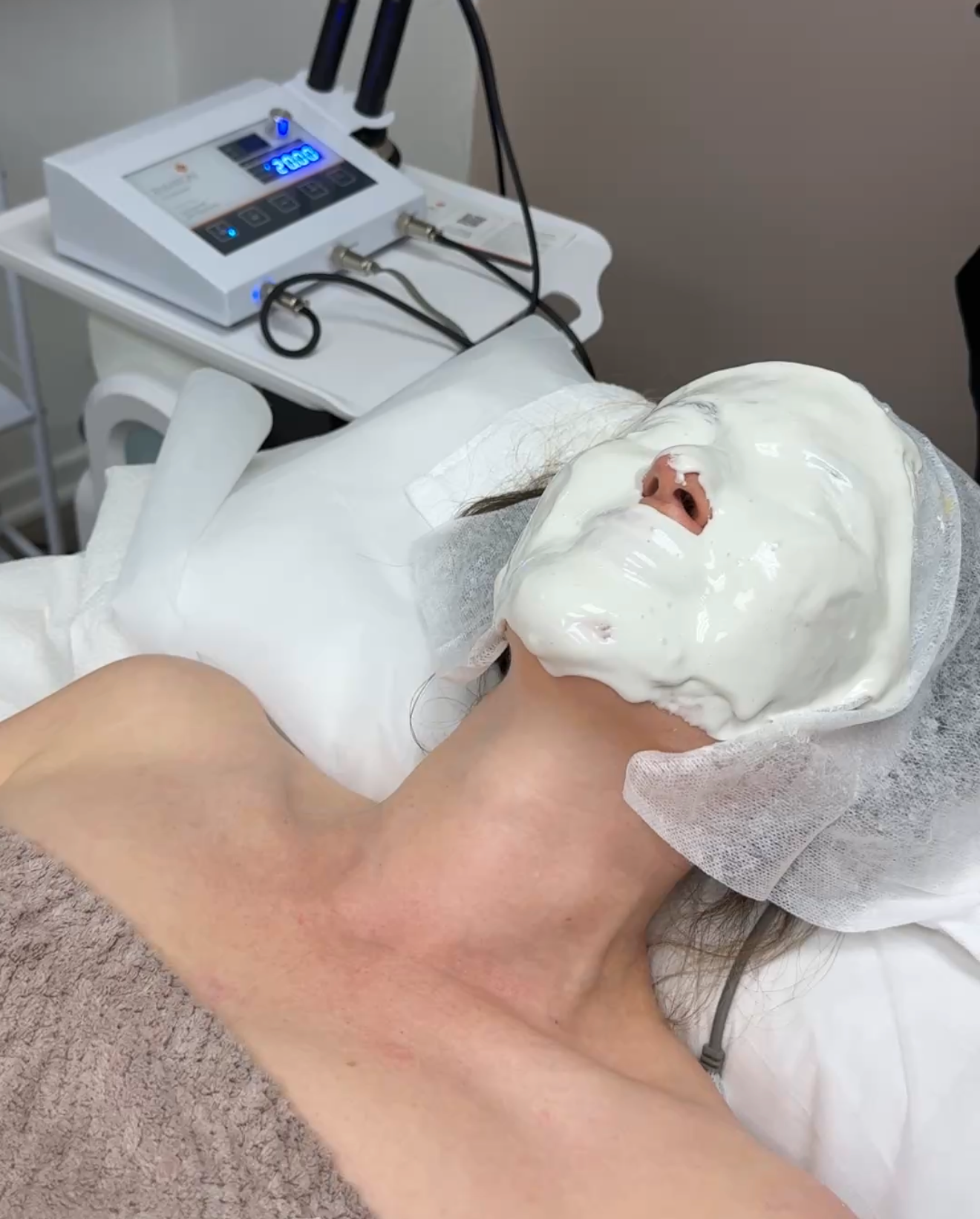 Person with white mask on face in spa setting; skin treatment.
