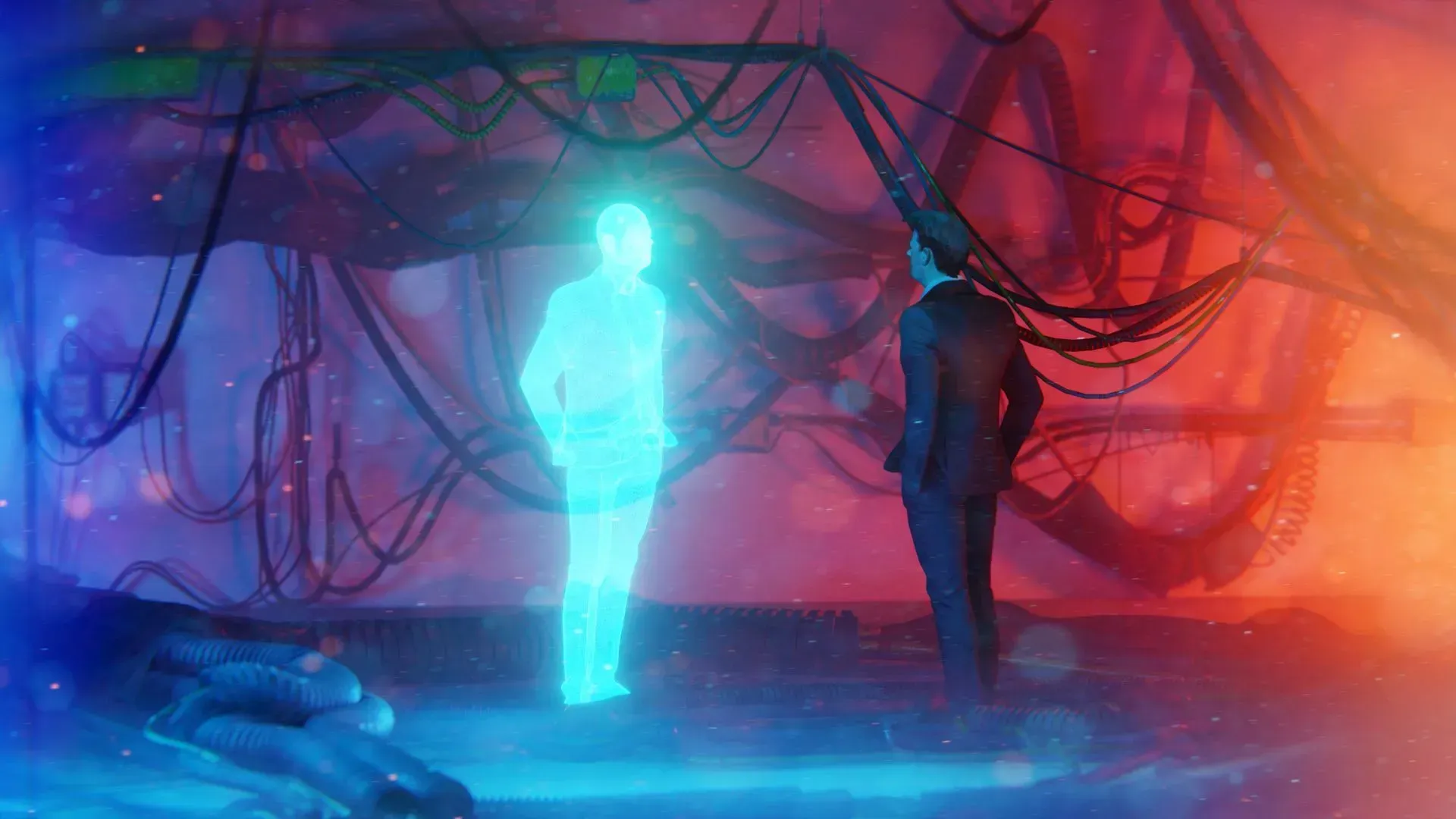 A person in a suit faces a glowing blue holographic figure in a dimly lit, cable-filled room with red and blue lighting.