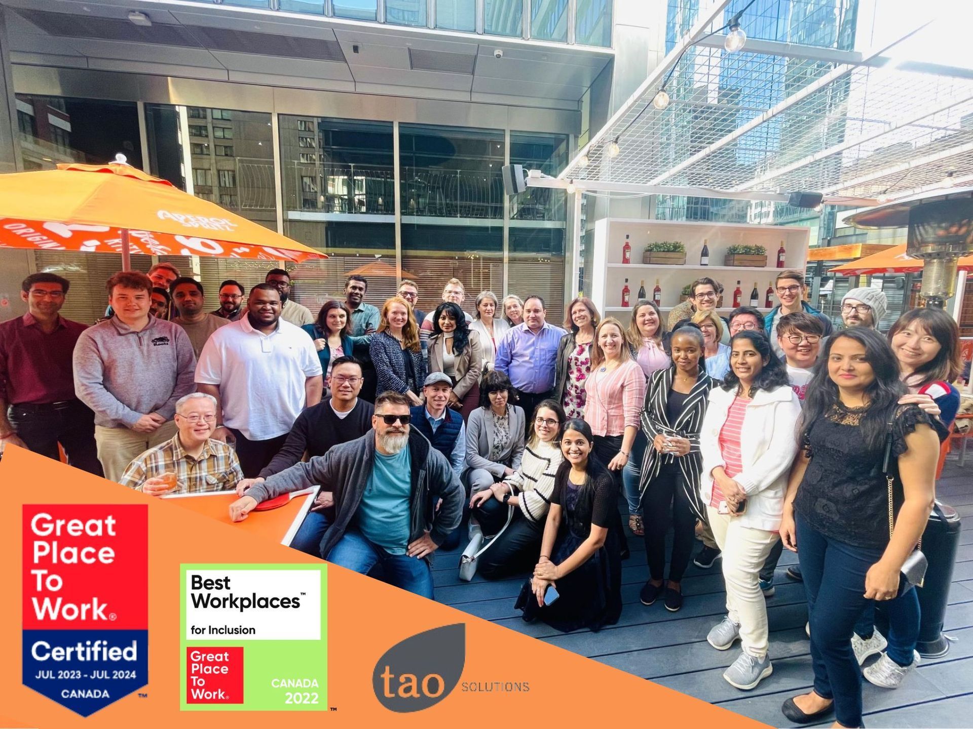 A diverse group of people smiling for a photo on an outdoor patio, with Great Place to Work certification logos visible.