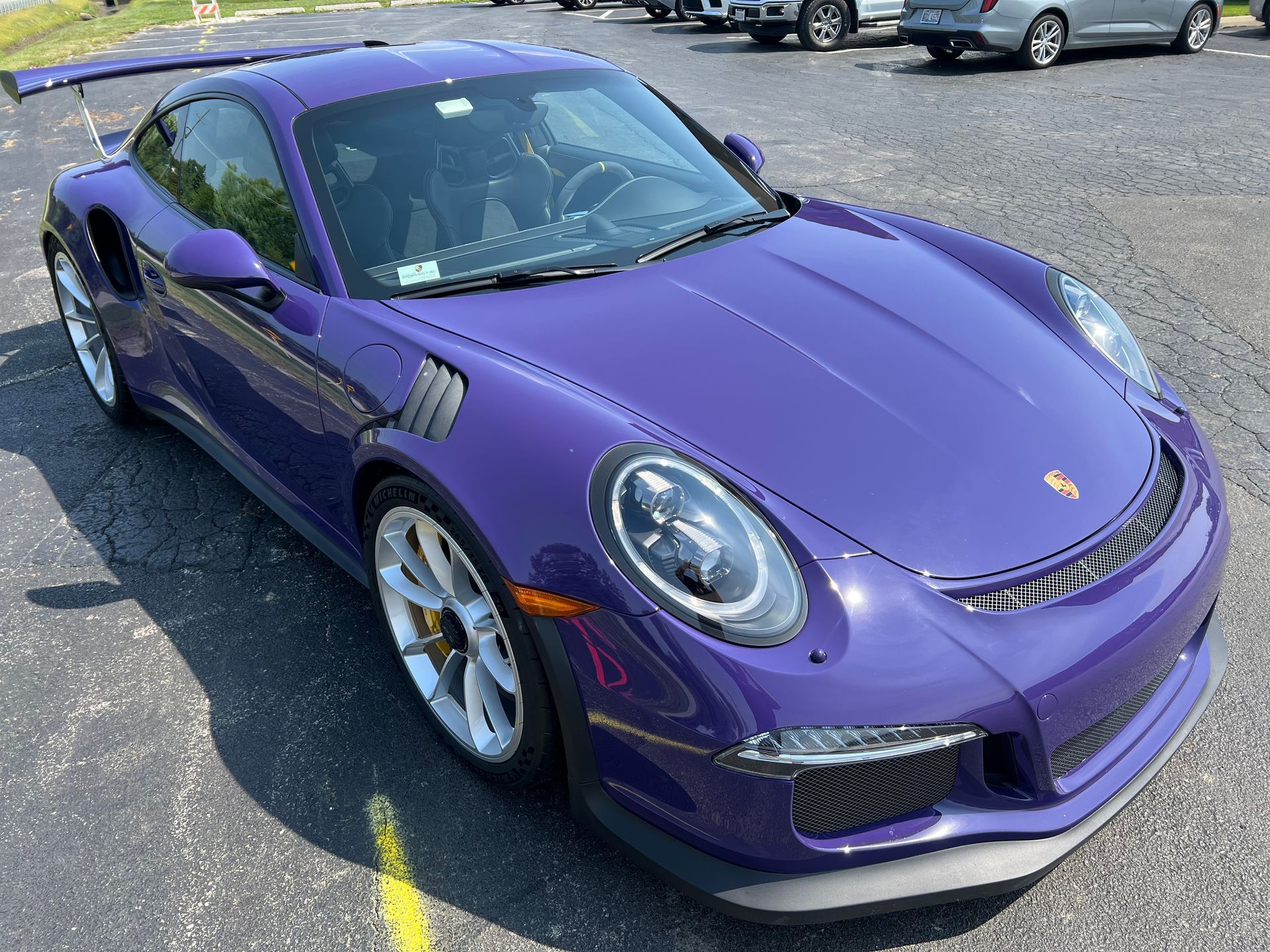 Purple Porsche 911 GT3 RS sports car parked on asphalt.
