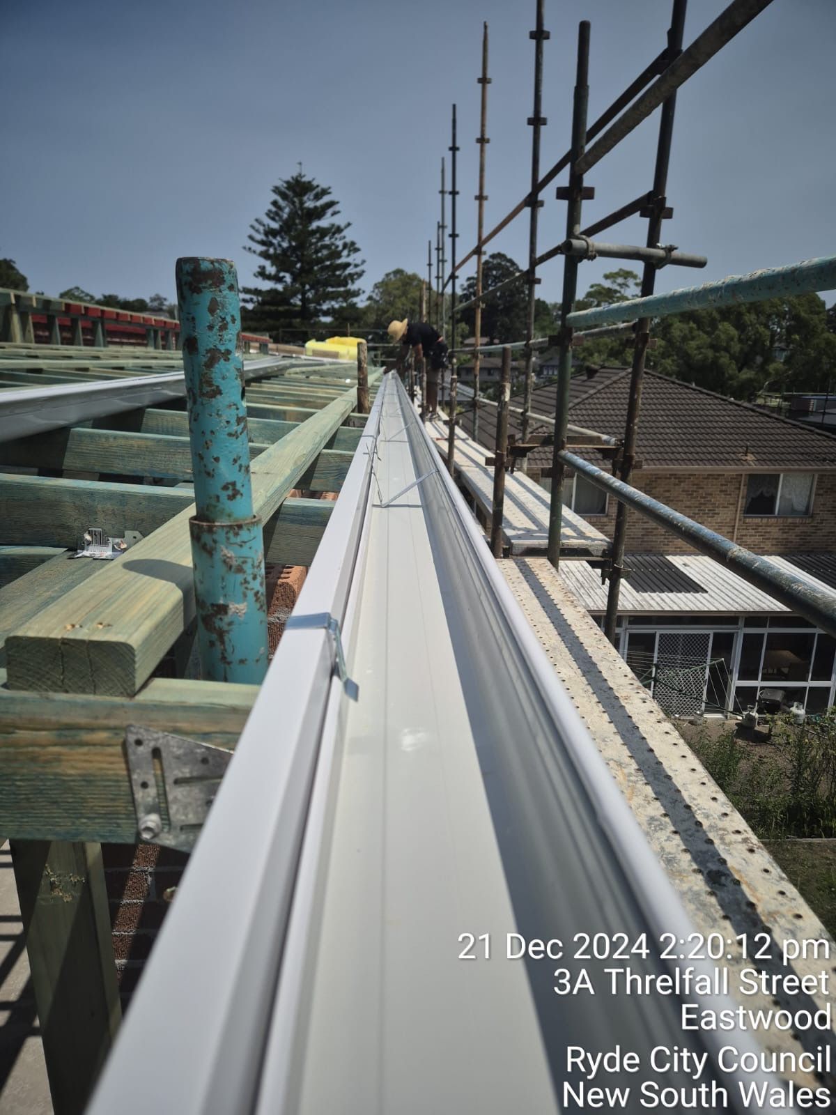 Scaffolded rooftop walkway under construction with timber framing and guard rails along a house exterior