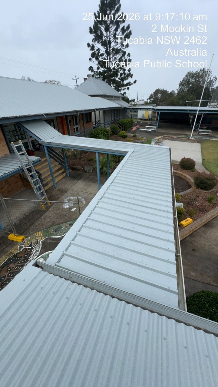 Covered metal walkway between buildings in a school courtyard, viewed from above, on a rainy day