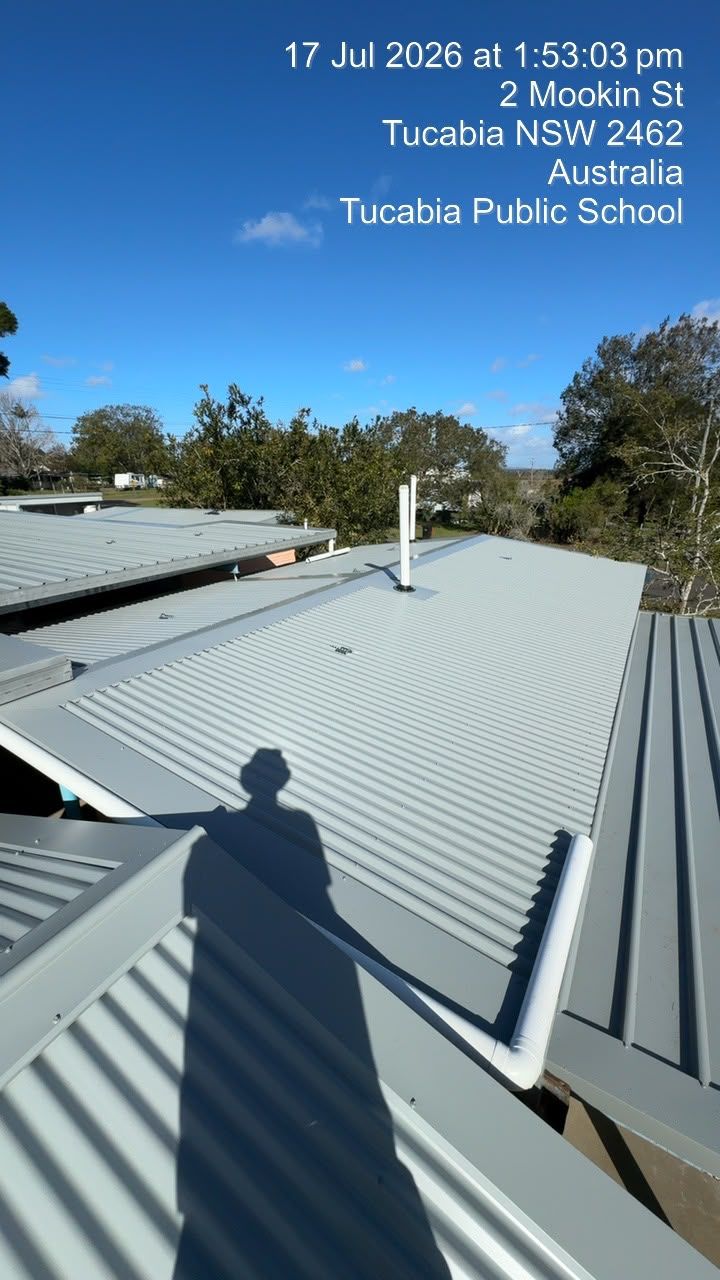Rooftop with gray metal sheets and white vents under a blue sky at Tucka Tucka Public School.