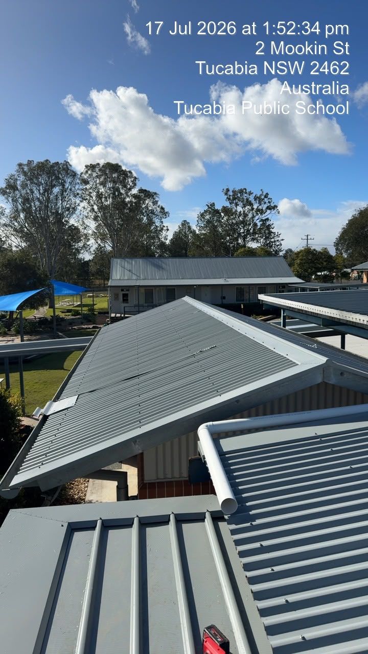 Rooftops at Taucau Tropical School under a bright blue sky, with trees and a building in the background