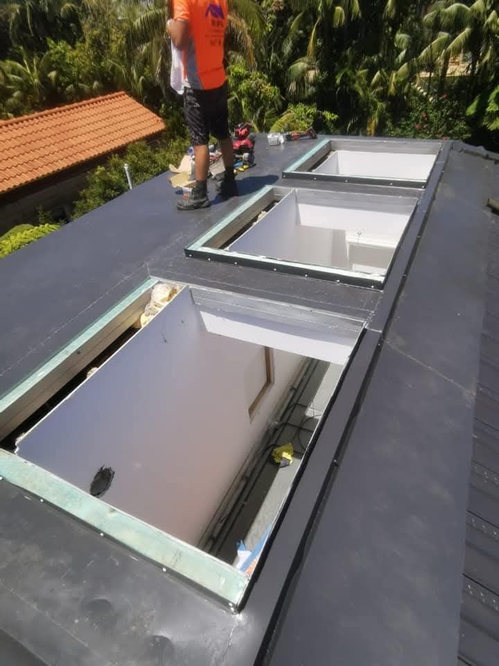 Open rooftop skylight with a worker standing nearby and trees in the background