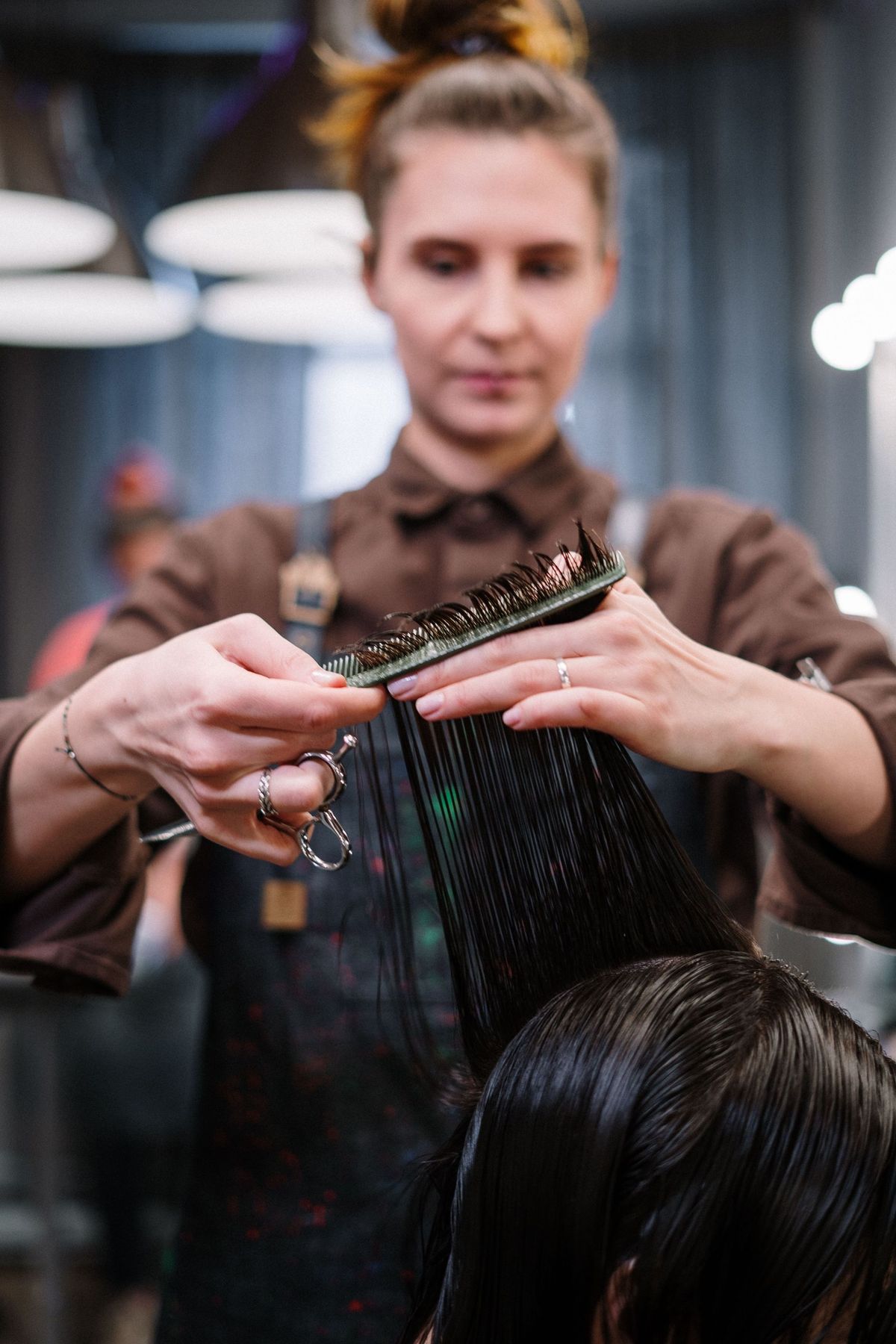 Stylist shaping a client's long hair with a comb in a salon chair