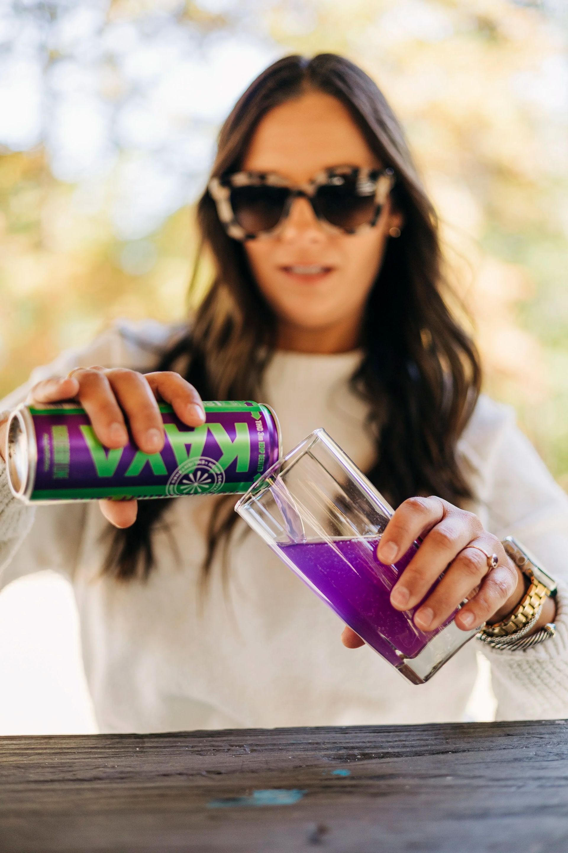 Person pouring a can of KAYA THC infused mocktail into a glass outdoors.