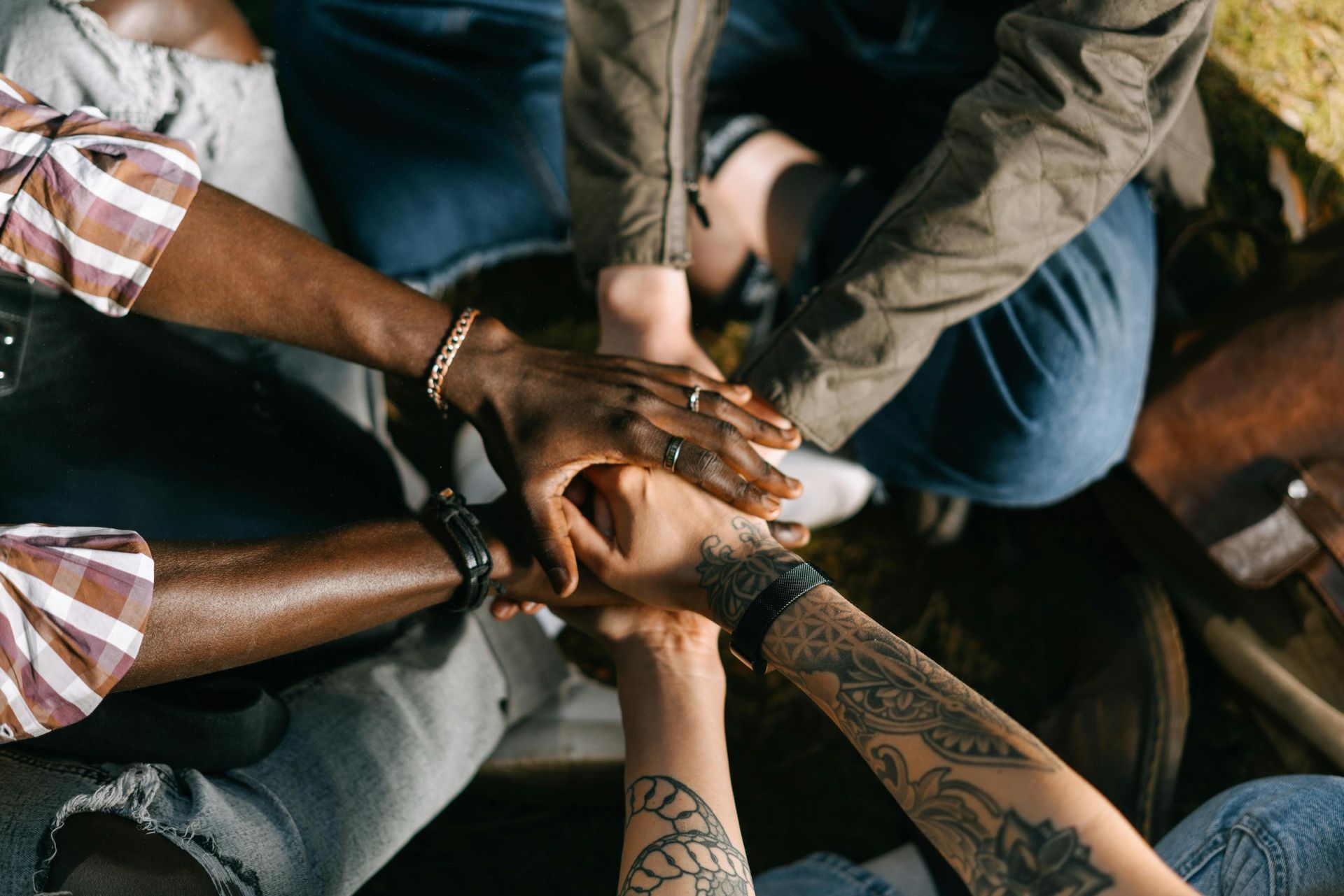 Hands of diverse people stacked together in a circle, symbolizing unity and teamwork.