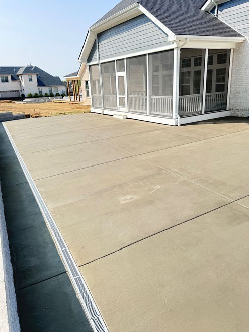 Concrete patio beside a screened porch on a sunny residential construction site