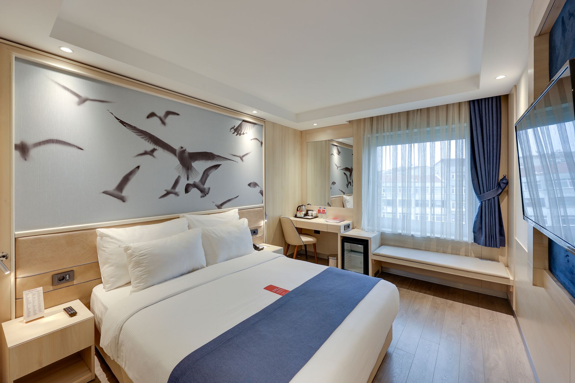 Hotel room with a bed, desk, and a wall with seagull art.