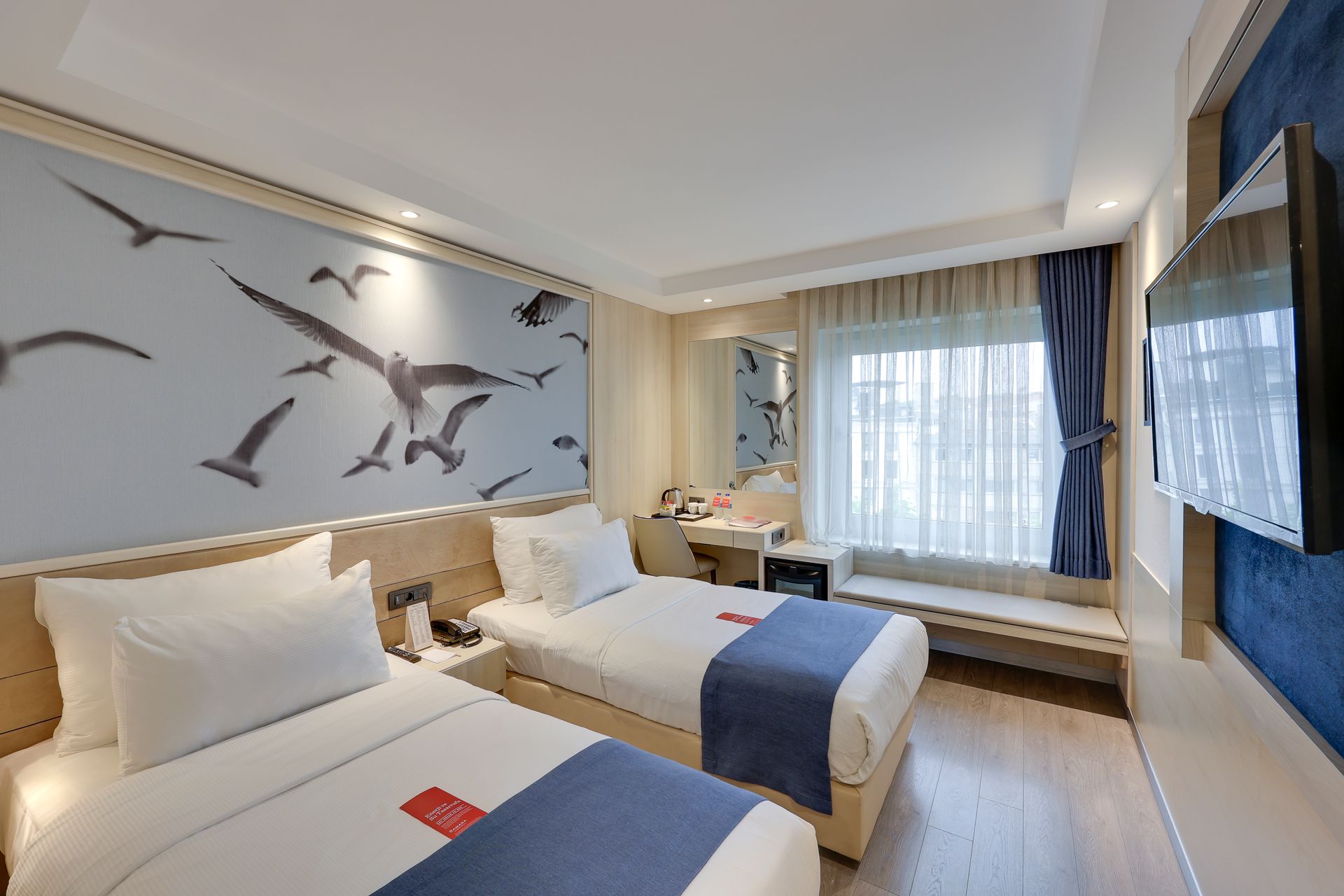 Twin hotel room with two beds, a window, and a seagull mural.