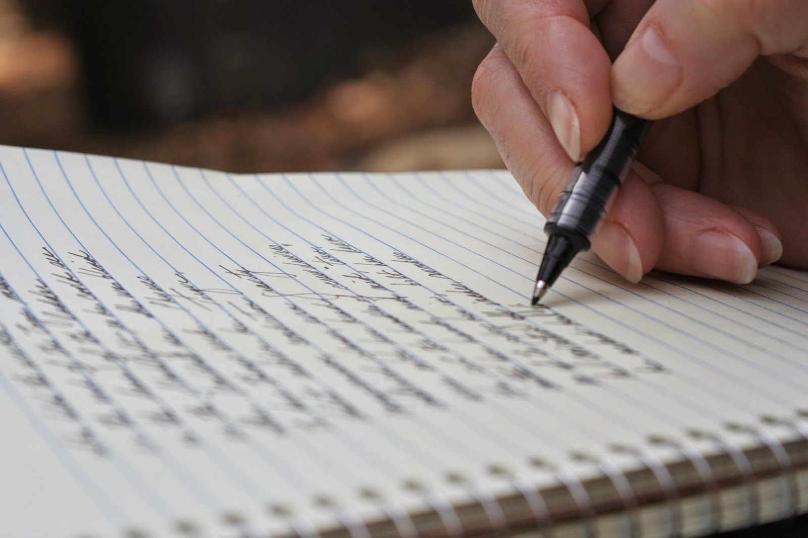 Uma pessoa está escrevendo em um caderno com uma caneta