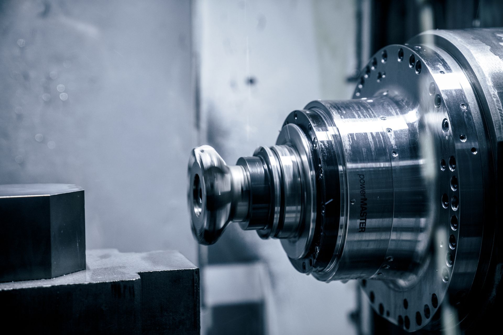 CNC-Maschine fräst ein Metallteil, Wasserdampf ist sichtbar.