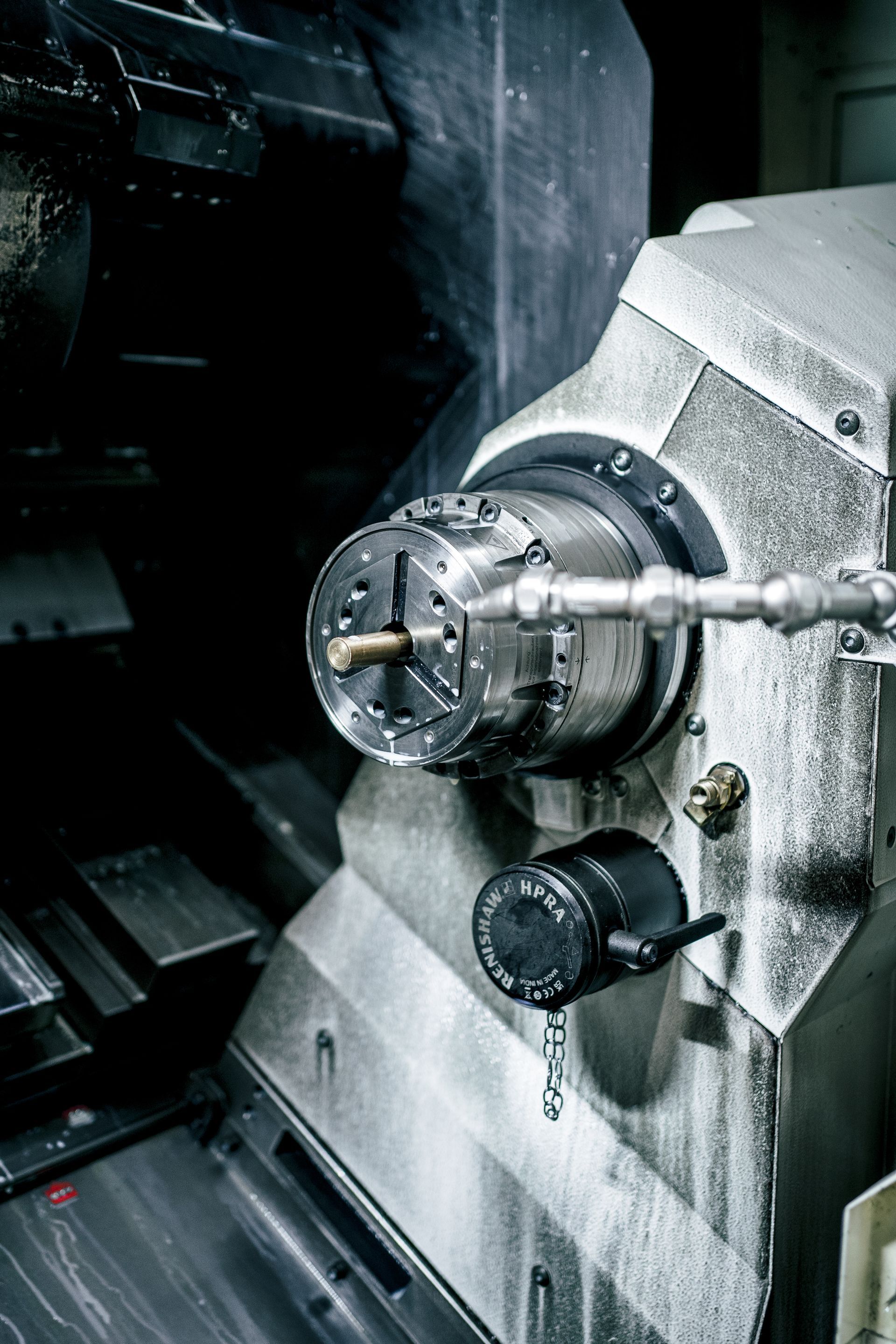 CNC-Maschine mit einer im Spannfutter eingespannten Metallstange in einer dunklen Industrieumgebung.